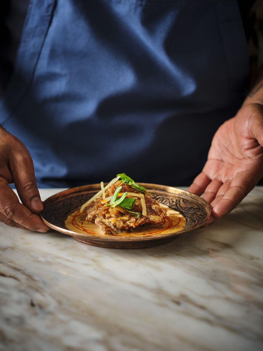 A plated regional Indian dish set down on the marble pass at GOAT, Auckland